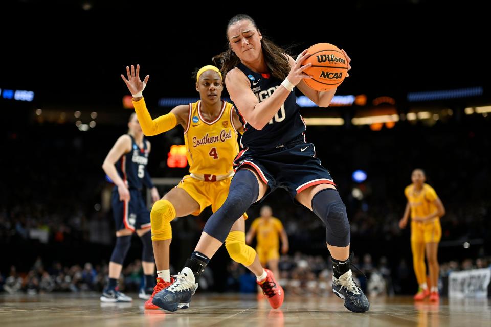 Huskies guard Nika Muhl grabs a rebound during the second half against Trojans guard Kayla Williams.