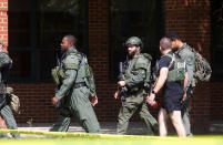 A Newport News Police Department Tactical Operations Unit patrols the perimeter of Heritage High School following a shooting, Monday, Sept. 20, 2021, in Newport News, Va. (Kaitlin McKeown/The Virginian-Pilot via AP)