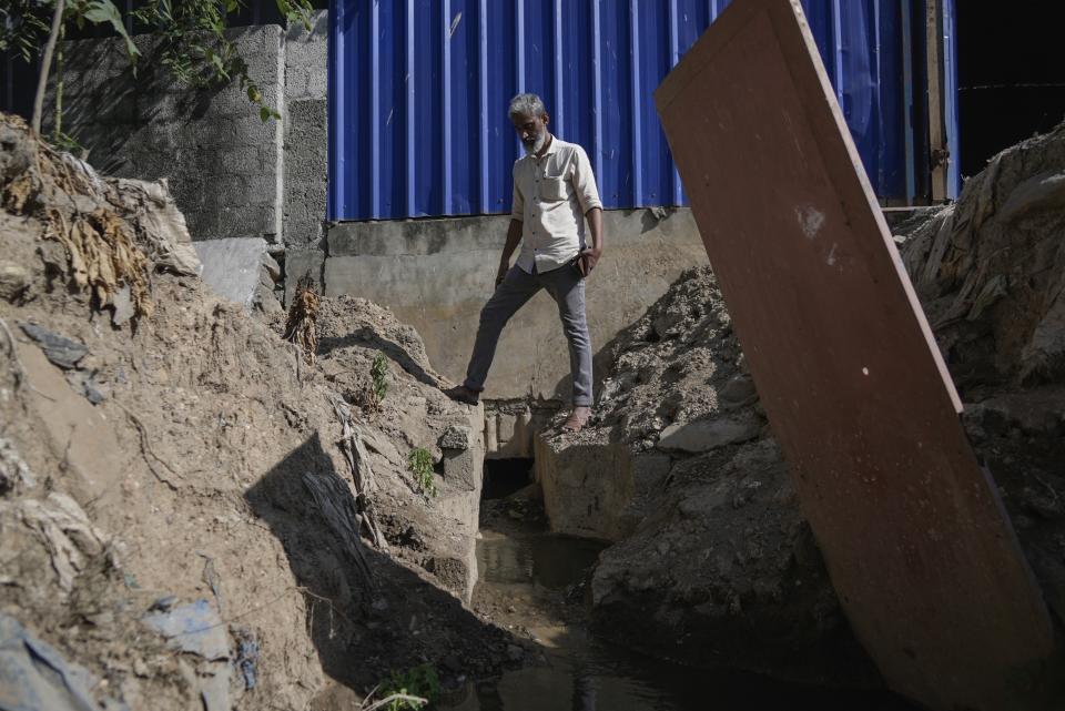 Activist Shabeer Mooppan stands next to a pipe discharging liquid directly into the Periyar River coming from the rear of a small manufacturer on the riverbanks in Eloor, Kerala state, India, Friday, March 3, 2023. Residents have risen up against the factories contaminating the river in the area and Shabeer has been in the forefront of the protests. (AP Photo)