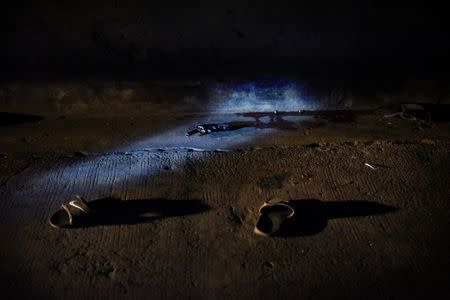 A pair of slippers and a gun lie amid blood spatter on the pavement under Macarthur bridge in the Sta Cruz district of Manila after police rushed three men, who were dead on arrival, to a public hospital on June 15, 2017. REUTERS/Dondi Tawatao