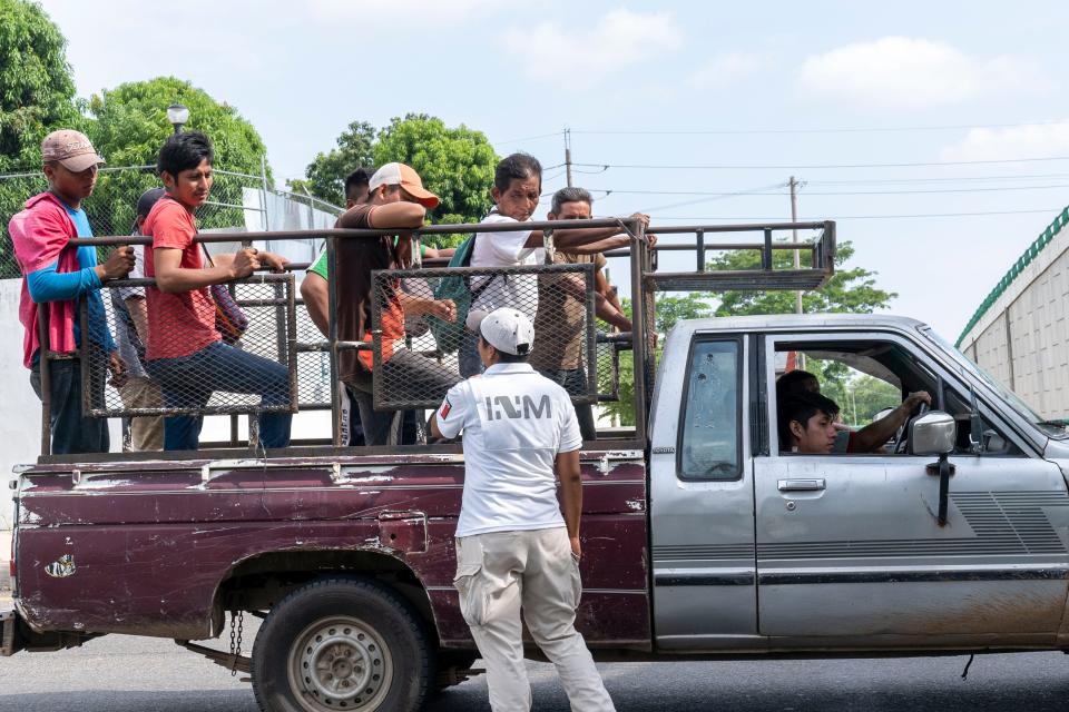 TAPACHULA, Mexico – Mexican National Guard troops stand watch as Mexican immigration authorities question two passengers in a pickup truck at a checkpoint on the northbound highway near Tapachula.