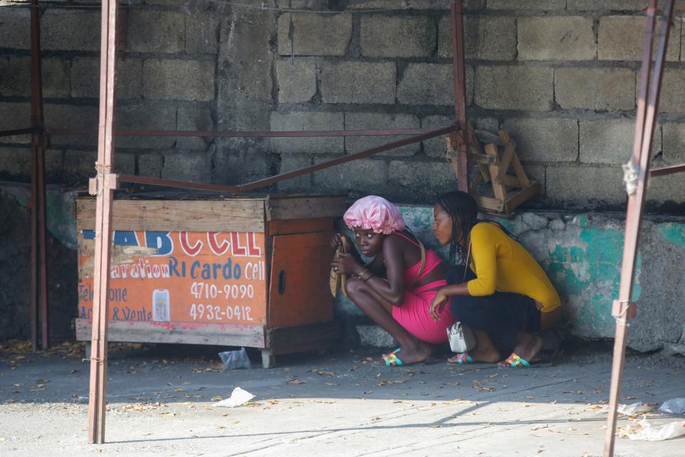 Women take cover during a gun battle between police and gang members in Port-au-Prince, Haiti.