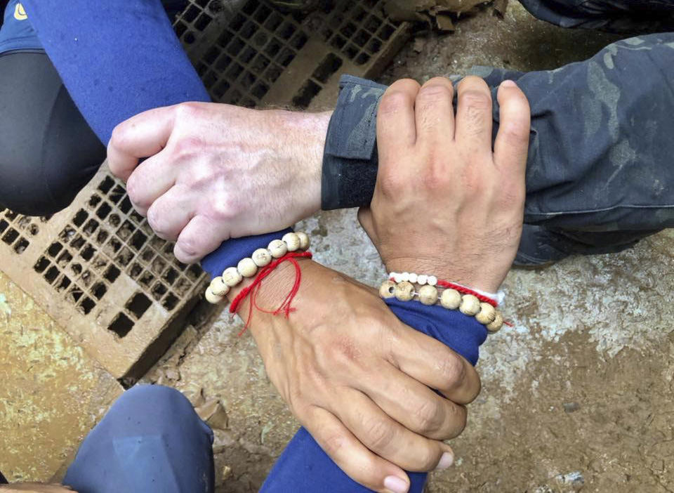This undated photo released via the Thailand Navy SEAL Facebook page on Sunday, July 8, 2018, shows rescuers hands locked with a caption reading “We Thai and the international teams join forces to bring the young Wild Boars home”. Source: AP