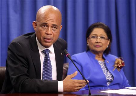 Haitian President Michel Martelly addresses a media conference, as Trinidad and Tobago's Prime Minister and chairperson of the Caribbean Community (CARICOM) Kamla Persad-Bissessar looks on, at the Diplomatic Centre in St Ann's, on the outskirts of the capital Port-of-Spain, November 26, 2013. REUTERS/Andrea De Silva