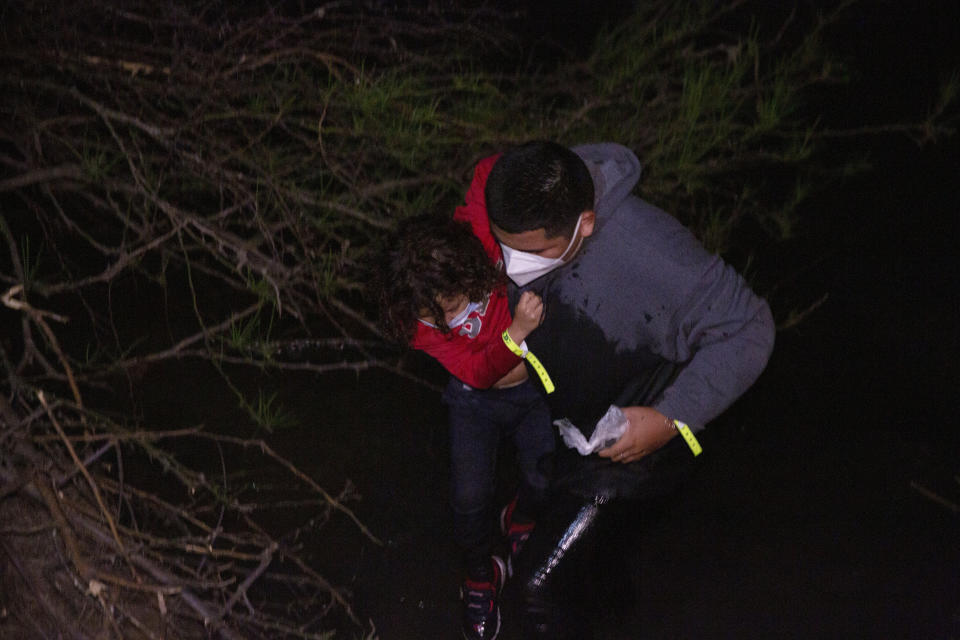 A father helps her daughter after they were smuggled on an inflatable raft across the Rio Grande, in Roma, Texas Saturday, March 27, 2021. (AP Photo/Dario Lopez-Mills)