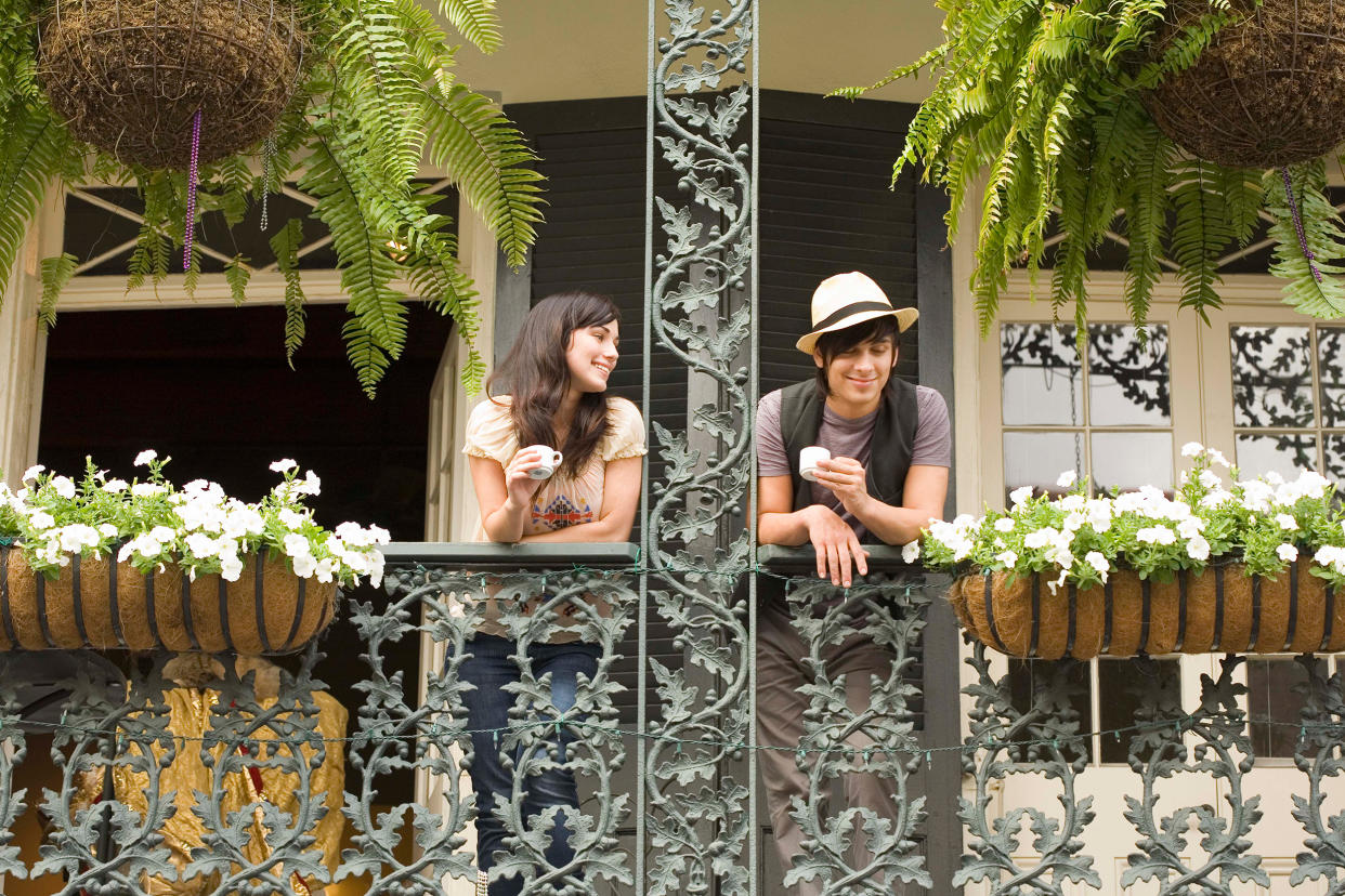 Couple on balcony in New Orleans, Louisiana, drinking coffee and leaning over the railing. (Jupiterimages / Getty Images)