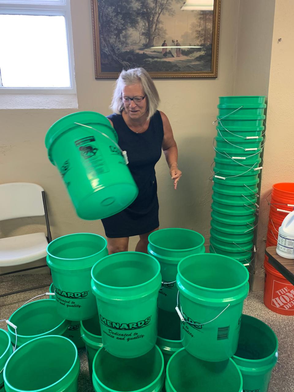 Becky McFarlin is surrounded by Flood Buckets to be packed for disaster relief in Iowa.