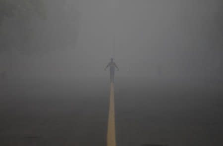 FILE PHOTO - A man walks along a road on a smoggy winter morning in New Delhi, December 21, 2017. REUTERS/Saumya Khandelwal