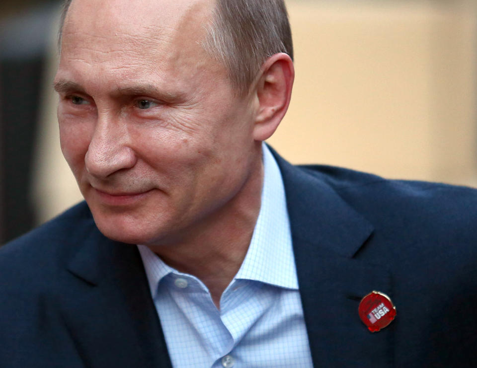 Russian President Vladimir Putin wears a Team USA pin while visiting USA House in the Olympic Village during the 2014 Winter Olympics on Friday, Feb. 14, 2014, in Sochi, Russia. (AP Photo/Marianna Massey, USOC Pool)