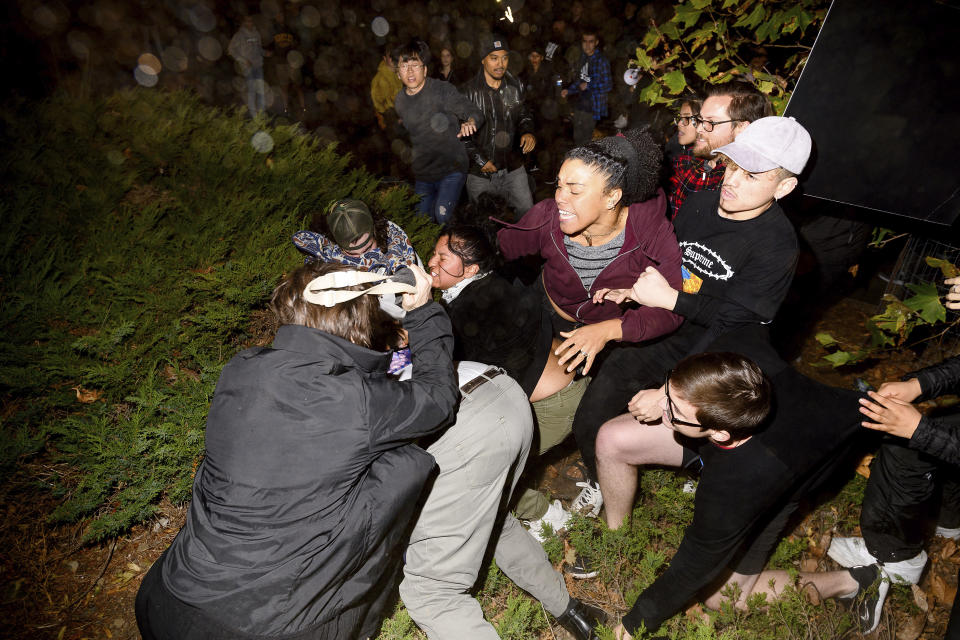 A man pushed by protesters is surrounded as he falls to the ground while leaving a speech by conservative commentator Ann Coulter at the University of California, Berkeley, Wednesday, Nov. 20, 2019, in Berkeley, Calif. Hundreds of demonstrators gathered as Coulter delivered a speech titled "Adios, America!" (AP Photo/Noah Berger)
