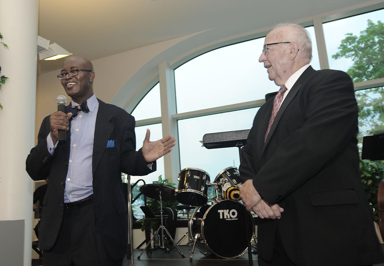 Monroe County Community College President Kojo Quartey (left) gives a speech during a retirement ceremony for President Emeritus David Nixon (right) in 2013 at the La-Z-Boy Center.