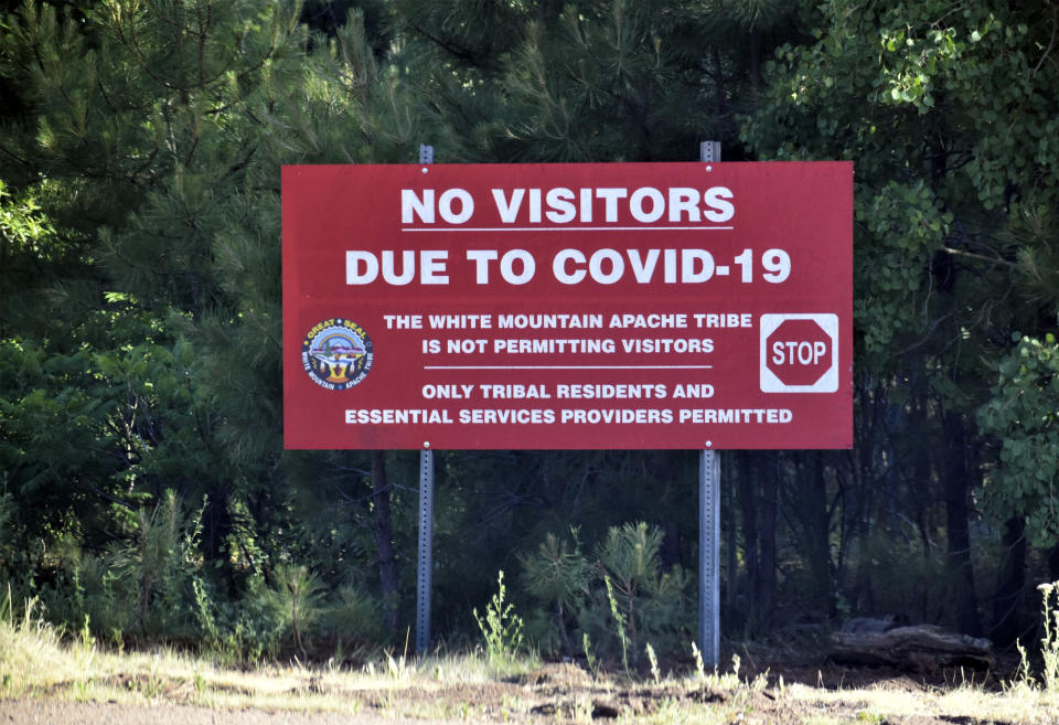 In this Thursday, June 25, 2020 photo provided by C.M. Clay, a sign alerts motorists that visitors are not allowed on the Fort Apache Indian Reservation in eastern Arizona. The reservation, home to the White Mountain Apache Tribe, will be under lockdown this weekend to help slow the spread of the coronavirus. (C.M. Clay/White Mountain Apache Tribe via AP)