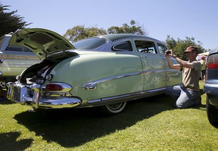 A man takes a photograph of a 1953 Hudson during the "Worst of Show" at the Concours d'Lemon, part of the Pebble Beach Concours d'Elegance in Seaside, California, August 15, 2015. REUTERS/Robert Galbraith