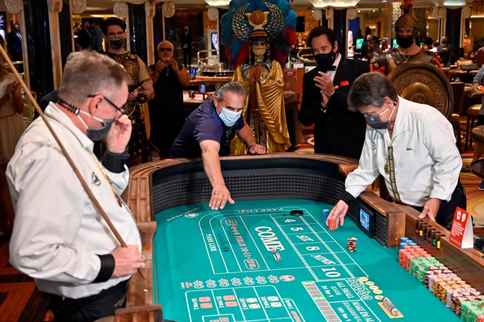 Craps player Ben Laparne rolls the dice as entertainer Wayne Newton, second from right, looks on at Caesars Palace in Las Vegas on Thursday after the property opened for the first time since being closed March<TH>17 because of the coronavirus pandemic.