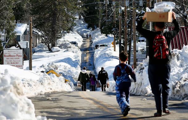 PHOTO: People carry donated food after a series of winter storms dumped heavy snowfall in the San Bernardino Mountains in Southern California, March 3, 2023 in Crestline, Calif. (Mario Tama/Getty Images)