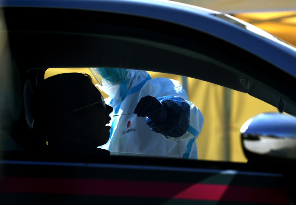 A medical professional administers a COVID-19 test during a drive-thru testing station on March 26, 2020 in Daly City, Calif. New coronavirus testing stations are opening up each day in the San Francisco Bay Area.