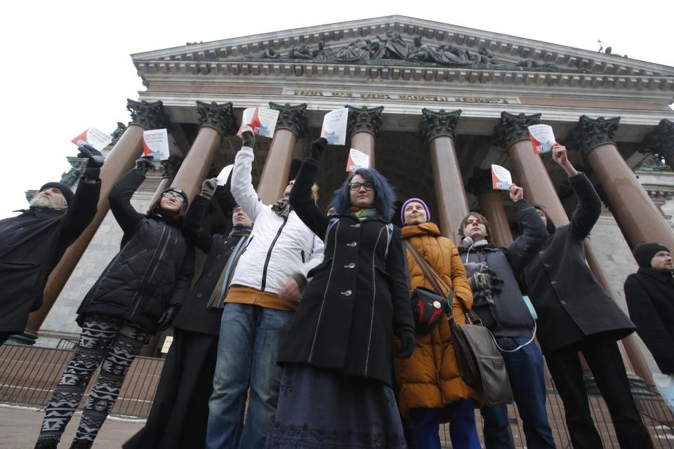 Protesters against the transfer of St. Isaac's Cathedral to the Russian Orthodox Church hold up the Constitution of the Russian Federation in front of the Cathedral in St. Petersburg, Russia, Thursday, Jan. 12, 2017. Authorities in Russia's second-largest city defend a controversial decision to give a city landmark cathedral to the Russian Orthodox Church. (AP Photo/Dmitri Lovetsky)