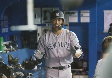 Mar 29, 2018; Toronto, Ontario, CAN; New York Yankees right fielder Giancarlo Stanton (27) celebrates in the dugout after hitting a home run in the ninth inning against the Toronto Blue Jays at Rogers Centre. The Yankees won 6-1. Mandatory Credit: Nick Turchiaro-USA TODAY Sports