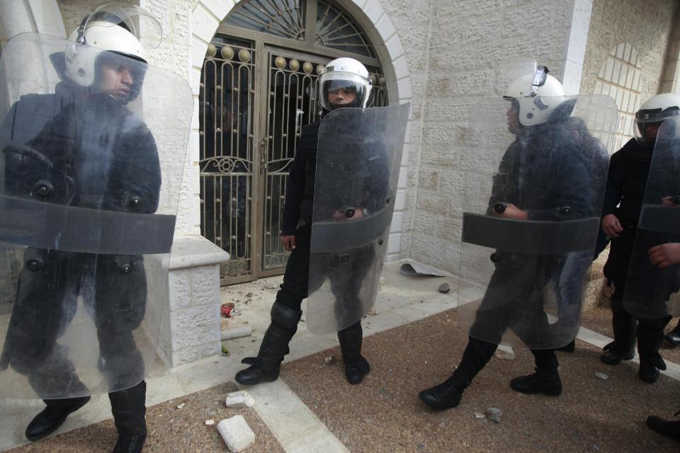 Palestinian riot police block against protesters the entrance of the hotel where groups of Israelis and Palestinians hold a meeting in the West Bank city of Ramallah, Thursday, Jan. 9, 2014. Palestinians threw rocks Thursday at a West Bank hotel, shattering windows and breaking up a meeting of Israeli and Palestinian peace activists. (AP Photo/Majdi Mohammed)