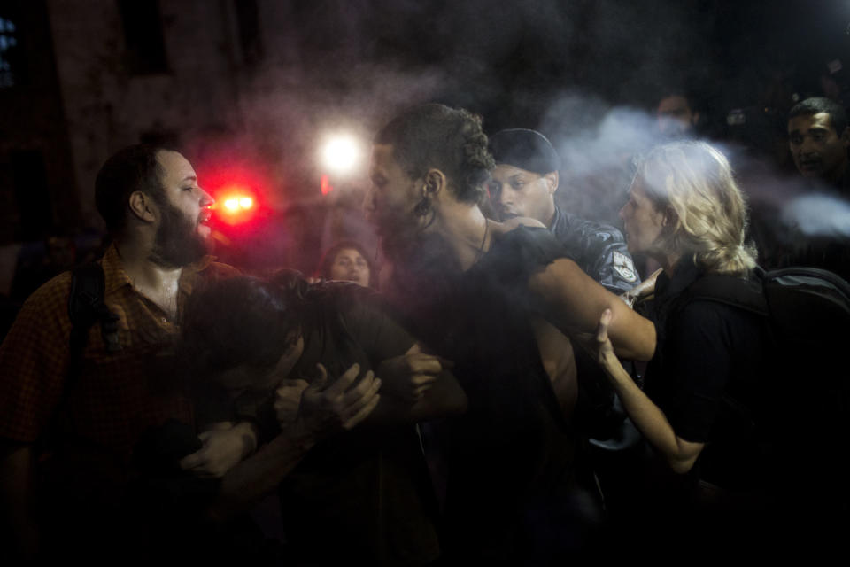 Supporters of the indigenous people who have been occupying the old Indian Museum are grabbed by riot police as they blocked the road outside the museum in Rio de Janeiro, Friday, March 22, 2013. The clash Friday is a bid to expel the group, some of whom have been squatting in the crumbling complex for years. The Indian museum has been at the center of a drawn-out legal battle between the several dozen Indians who've been living there for years and state and local authorities. Officials initially wanted to raze the complex as part of renovations ahead of Brazil's 2014 World Cup. (AP Photo/Felipe Dana)