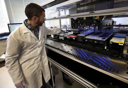 Technician Matthew Smith loads a robotic DNA sample automation machine at a Regeneron Pharmaceuticals Inc. laboratory at the biotechnology company's headquarters in Tarrytown, New York March 24, 2015. REUTERS/Mike Segar