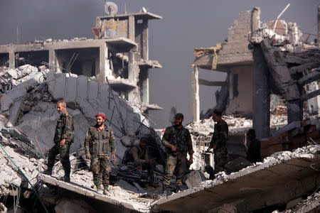 Syrian army soldiers stand on the rubble of damage buildings in al-Hajar al-Aswad, Syria May 21, 2018. REUTERS/Omar Sanadiki