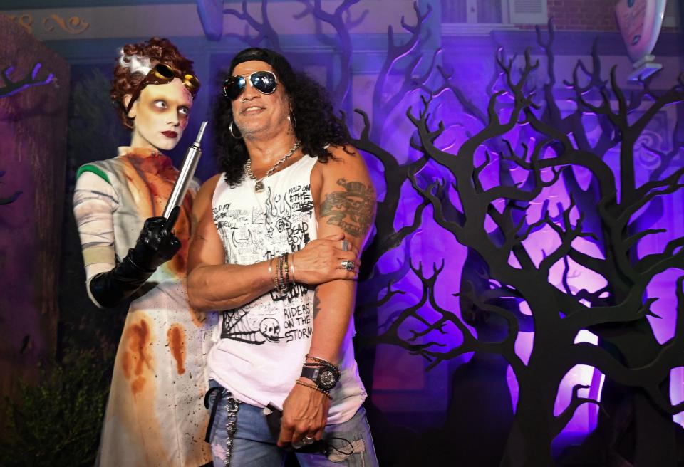 Musician Slash poses with a costumed actress in front of 