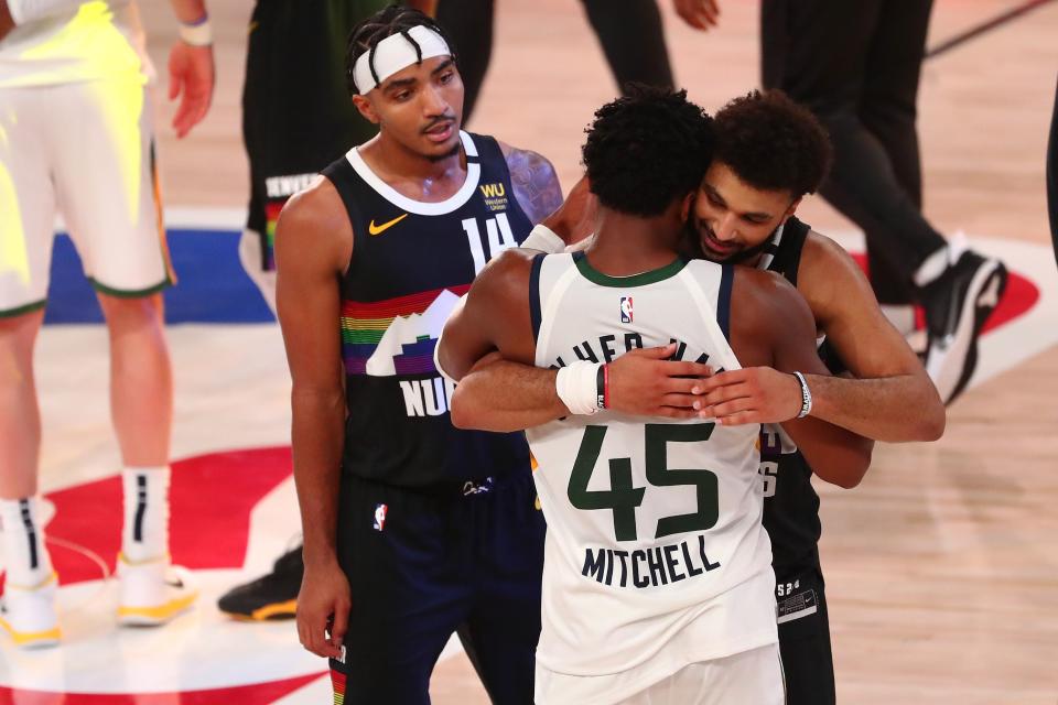 Denver Nuggets guard Jamal Murray (facing camera) and Utah Jazz guard Donovan Mitchell (45) embrace as Denver guard Gary Harris (14) looks on after a victory by the Nuggets in Game 7 of the first round of the 2020 NBA playoffs at ESPN Wide World of Sports Complex.