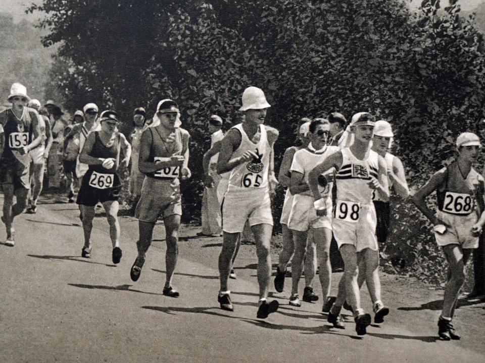 A black and white photo of people walk-racing in 1932 with trees behind them.