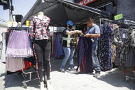 A sales transaction takes place at a clothing store Wednesday, May 27, 2020, in Los Angeles. California moved to further relax its coronavirus restrictions and help the battered economy. Retail stores, including those at shopping malls, can open at 50% capacity. (AP Photo/Marcio Jose Sanchez)