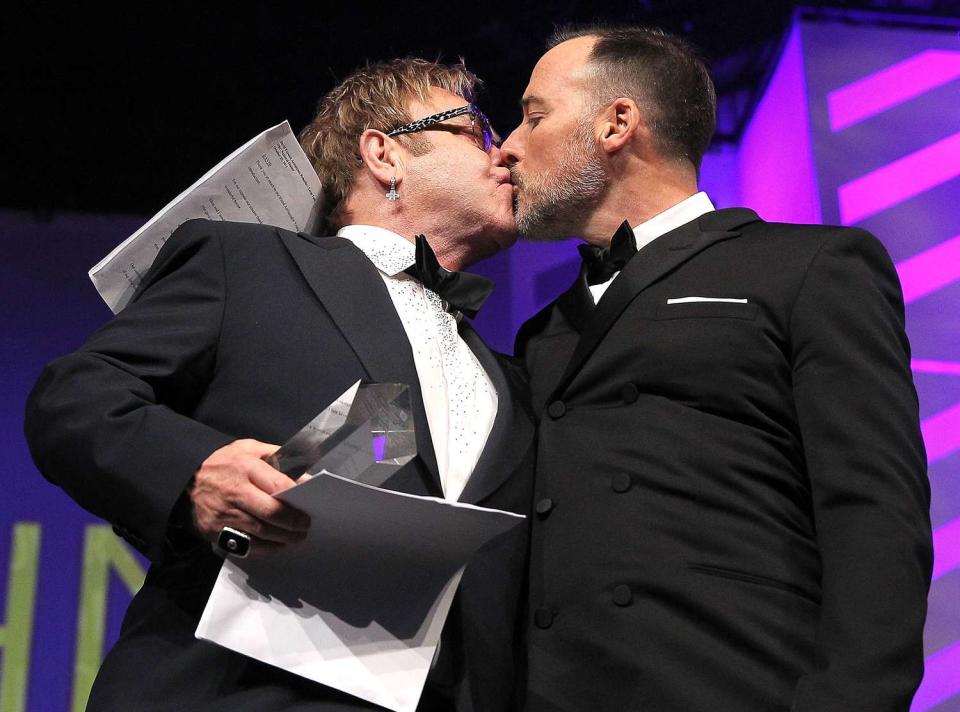 Sir Elton John (L) gives David Furnish a kiss at the 18th Annual HRC National Dinner at The Walter E. Washington Convention Center on October 25, 2014 in Washington, DC