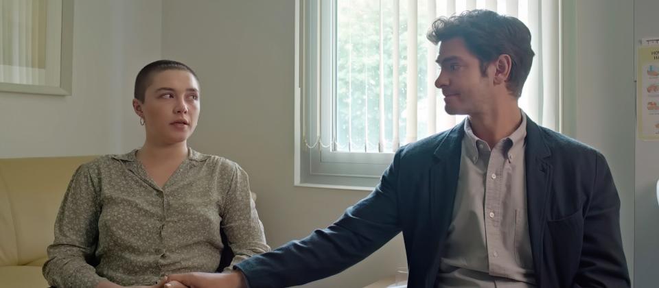 Florence Pugh and Andrew Garfield in a scene from the film We Live in Time. Garfield reaches for Pugh's hand.