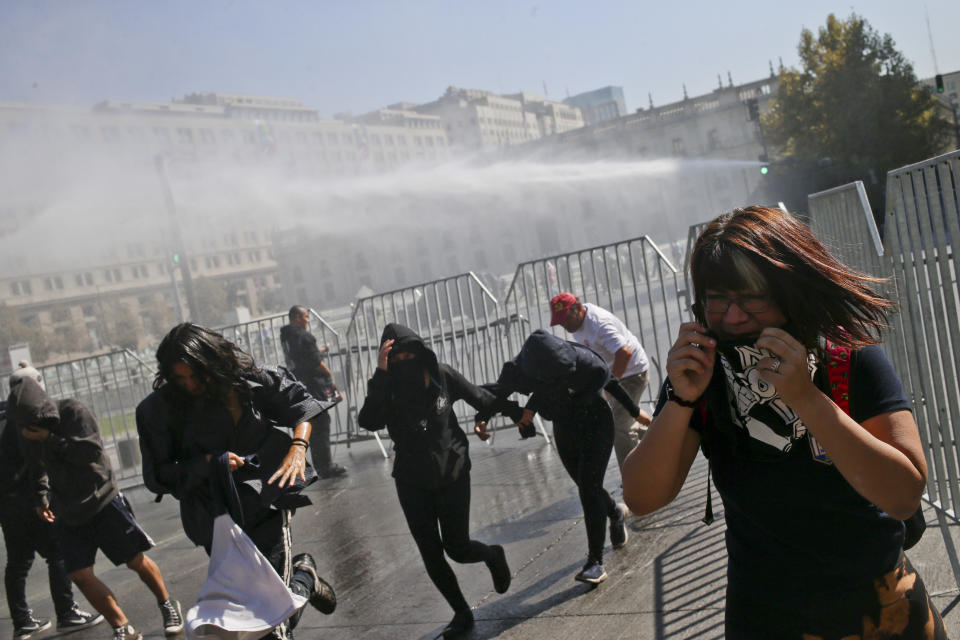 Manifestantes corren para protegerse mientras la policía lanza chorros de agua contra ellos durante una protesta contra una reforma educativa en Santiago de Chile el martes 11 de abril de 2017. Los manifestantes piden avances en materia de calidad educativa y la condonación de las deudas de sus con la banca. (AP Foto/Esteban Félix)