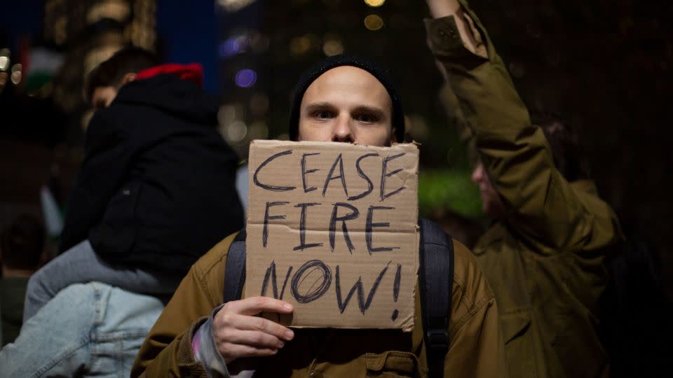 Derek, a 35-year-old massage therapist, holds a sign urging a ceasefire during the pro-Palestine rally in Columbus Circle. - Laura Oliverio/CNN