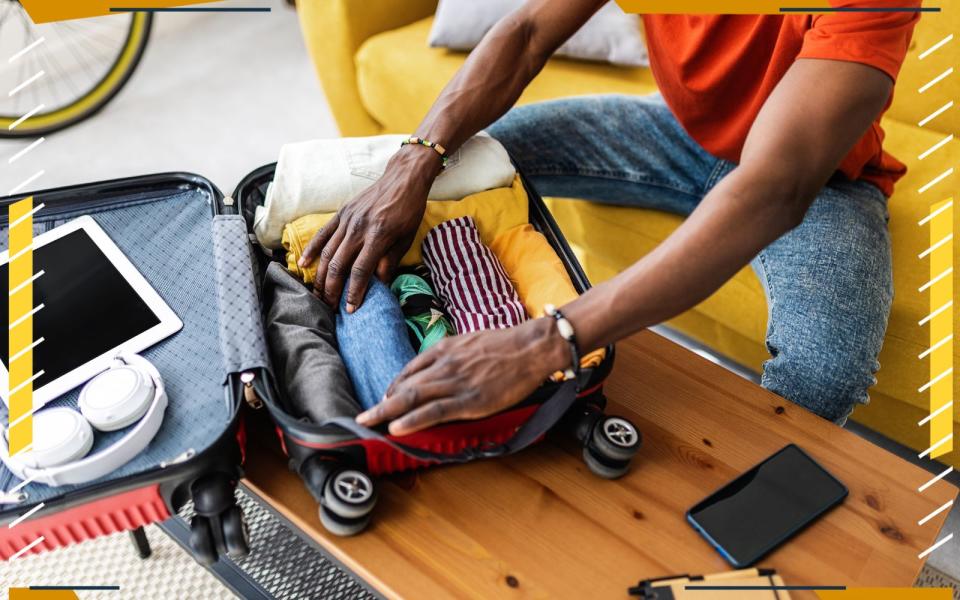 man packing a suitcase with clothing and ipad and headphones