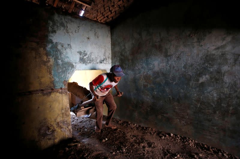 Kusno, a 67-year-old worker, pulls a wheelbarrow carrying soil to be used to raise the floor of a house affected by land subsidence at Tambaklorok in Semarang