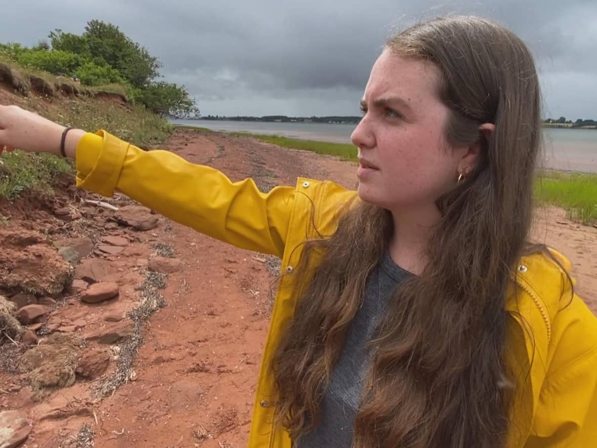 Erin Nelson points to an eroding coast. (Kirk Pennell/CBC - image credit)