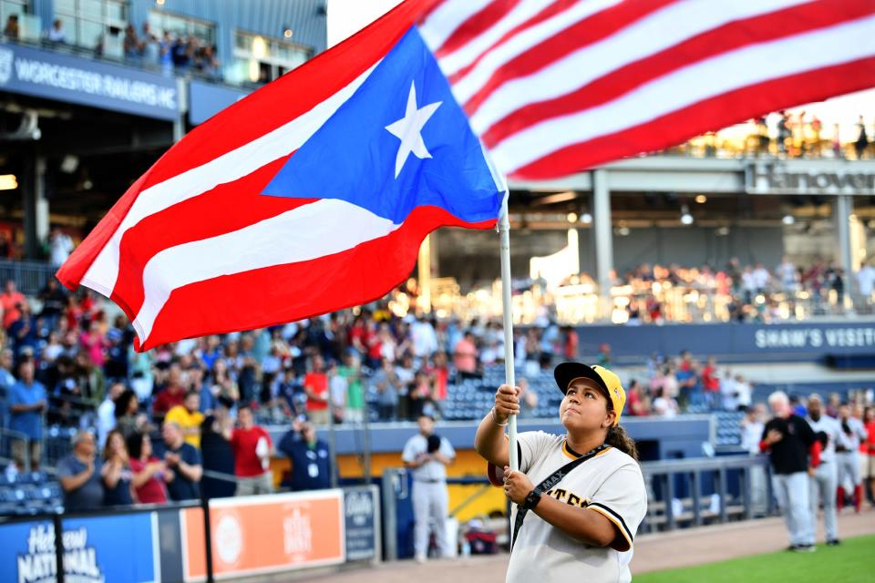 Mikayla Rivera of Lawrence holds the flag of Puerto Rico while both national anthems are delivered at Polar Park Thursday.