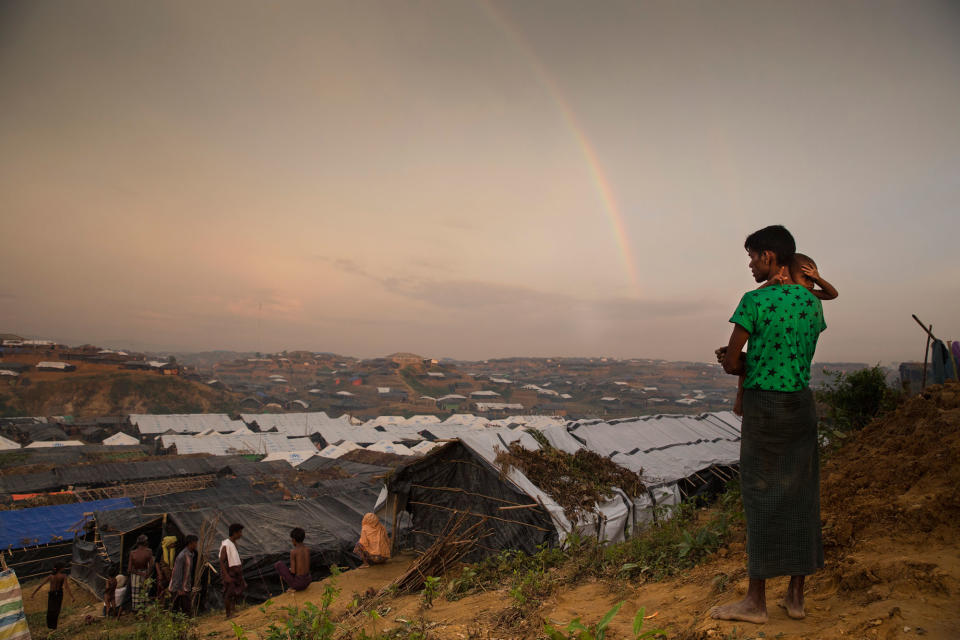 <p>A Rohingya man holds his child as he looks at a rainbow on a hill overlooking the Kutupalong refugee camp on September 22, 2017. (Photograph by Paula Bronstein/UNHCR) </p>
