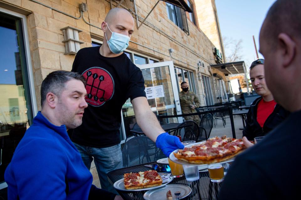 Server Jared Smith gives Sam Webster of New York his pizza order at Via 313 Pizza on March 3 in Austin, Texas. Businesses will be able to operate at full capacity beginning March 10.