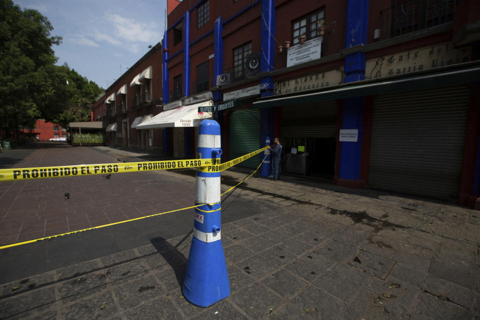A municipal employee closes off access to the main plaza of Coyoacan, in Mexico City, Saturday, April 4, 2020. Mexico has started taking tougher measures against the new coronavirus, but some experts warn the country is acting too late and testing too little to prevent the type of crisis unfolding across the border in the United States. (AP Photo/Fernando Llano)