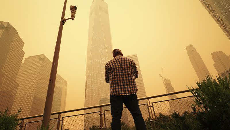 A man pauses to look at the smoke and haze shrouding One World Trade Center building in New York City, Wednesday, June 7, 2023. Intense Canadian wildfires are blanketing the northeastern U.S. in a haze, turning the air acrid and the sky yellowish gray.