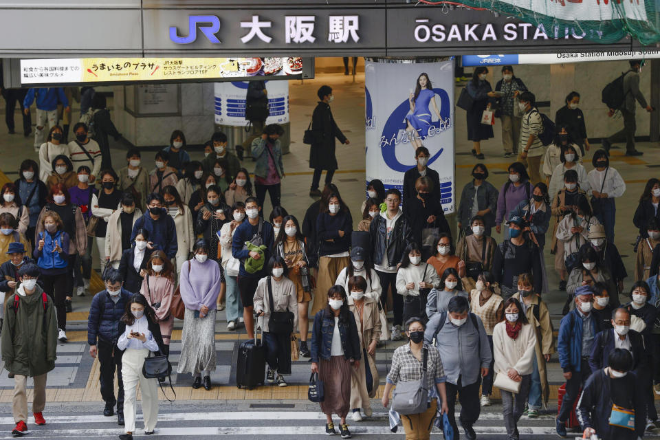 People wear face masks as they make their way in Osaka, western Japan Wednesday, March 31, 2021. Japan is set to designate Osaka and two other prefectures for new virus control steps Thursday as infections in those areas rise less than four months before the Tokyo Olympics. (Kyodo News via AP)