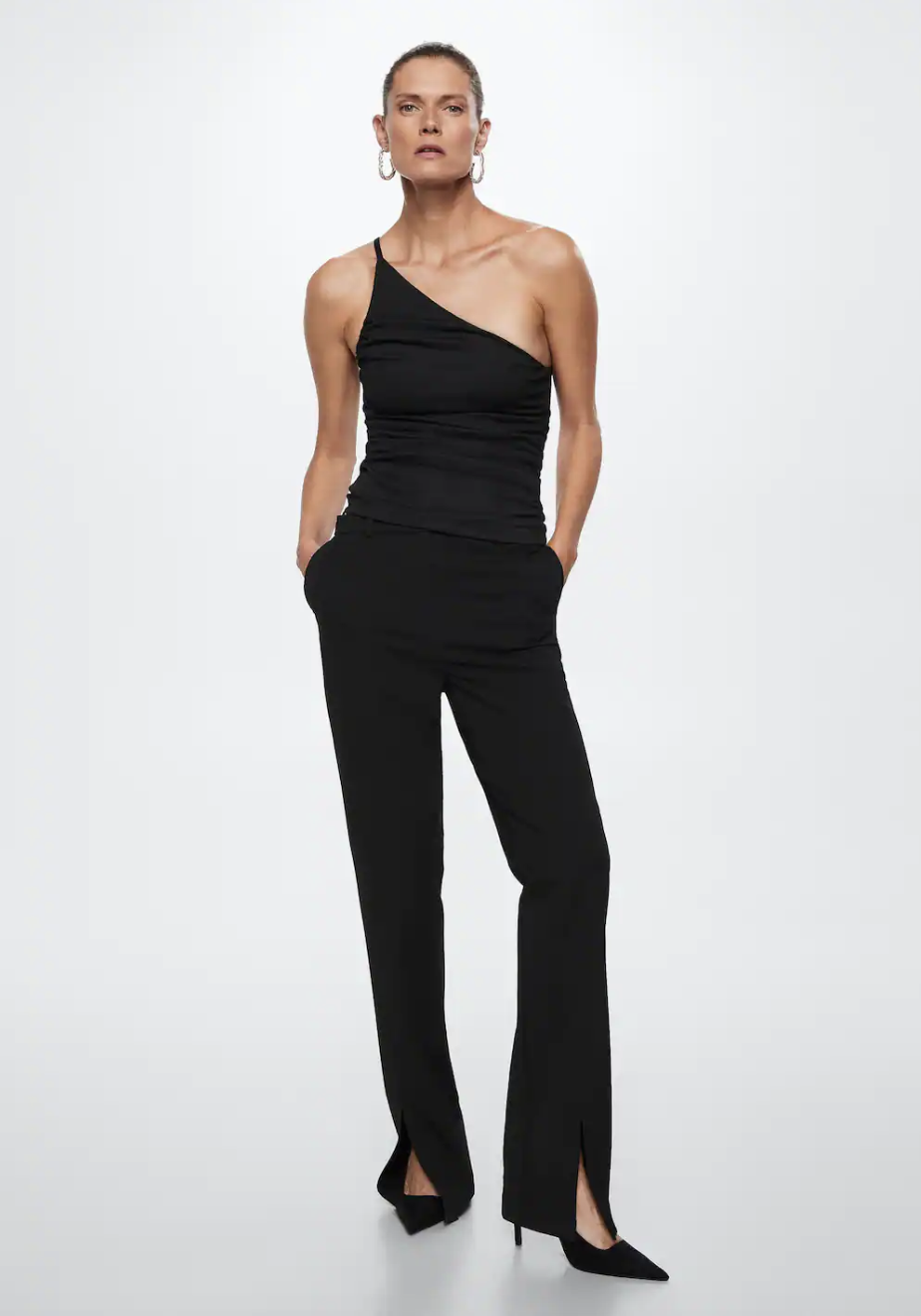 woman wearing black heels, black pants, and Asymmetrical Textured Top in black (photo via Mango)