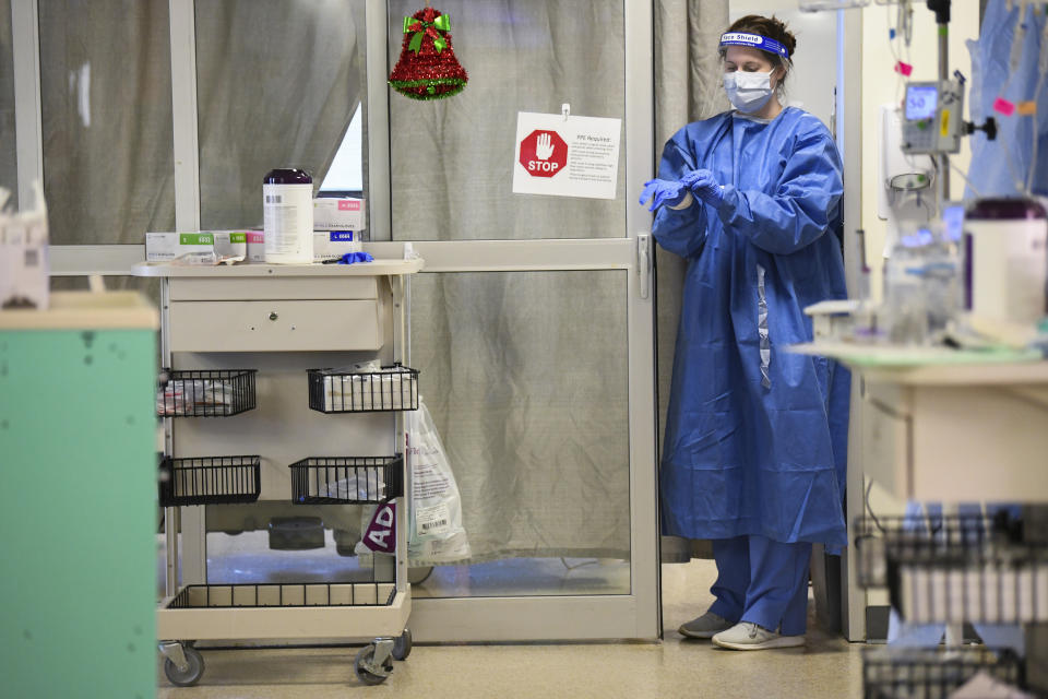 A nurse puts on rubber gloves before entering a COVID-19 patient's room in East Alabama Medical Center's intensive care unit Thursday, Dec. 10, 2020, in Opelika, Ala. Doctors and nurses caring for the sickest COVID-19 patients are doing what they can to get through the holidays while neighbors and friends indulge in Christmas parades and tree lightings. (AP Photo/Julie Bennett)