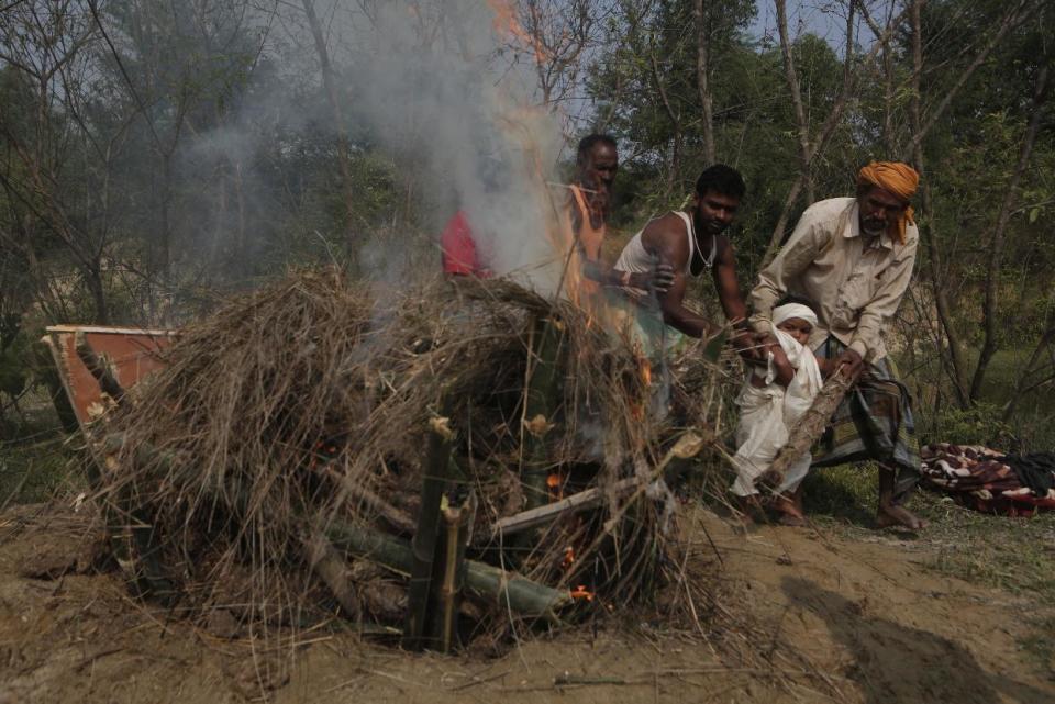In this Wednesday, Nov. 23, 2016 photo, a priest helps Shivendra Kumar Mandal, 3, nicknamed Siban, perform cremation rituals before lighting the funeral pyre of his father Balkisun Mandal Khatwe, at Belhi village in Saptari district of Nepal. Balkisun died in his sleep in Qatar, where he was working Habtoor Leighton Group, loading trucks to build new highways. Nepal is one of the poorest and least developed countries in the world, and Belhi is one of its poorest places. The Mandals live eight people to a room in one of about 700 mud-and-stick homes set among dry, sparse rice paddies. (AP Photo/Niranjan Shrestha)
