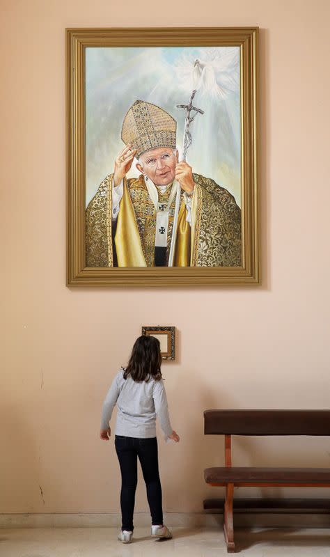 FILE PHOTO: Girl stands below a portrait of the late Pope John Paul II in the Roman Catholic church Most Holy Heart of Jesus in Rakovski