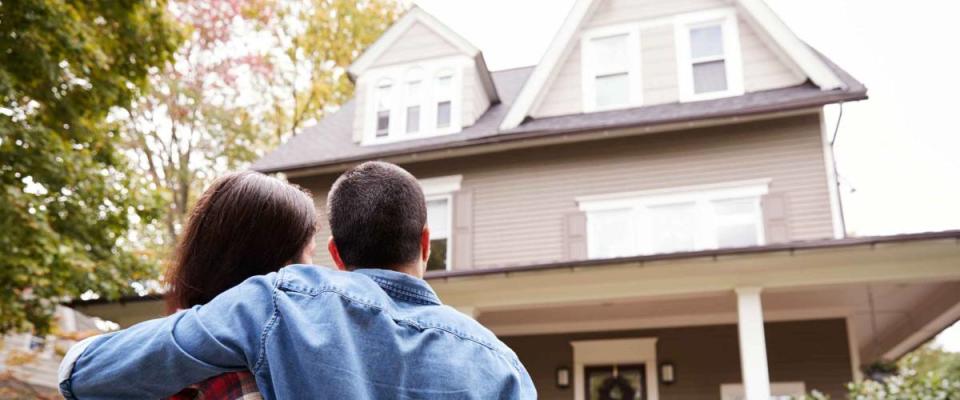 Rear View Of Loving Couple Looking At House