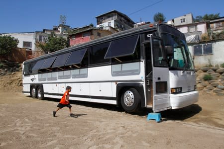 A migrant child runs towards a bus converted in a classroom as part of Schools On Wheels program by California's 'Yes We Can' organisation, in Tijuana