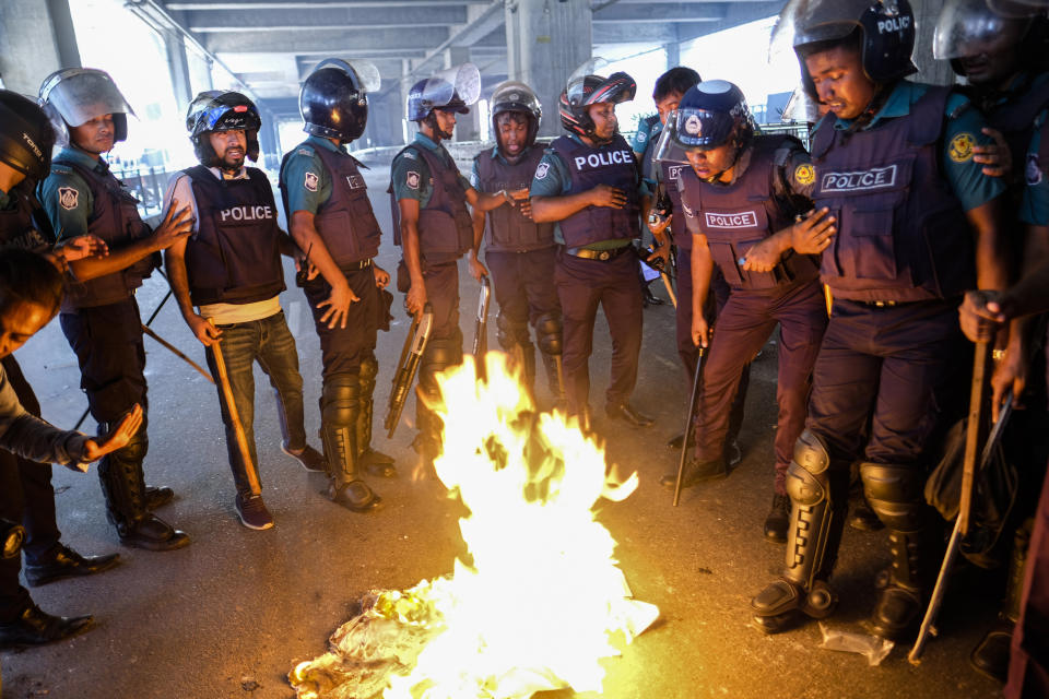 Police make a fire to save themselves from tear gas smoke as they disperse Bangladeshi garment factory workers who were blocking traffic demanding better wages at Dhaka-Mirpur area in Bangladesh, Thursday, Nov.2, 2023. (AP Photo/Mahmud Hossain Opu)